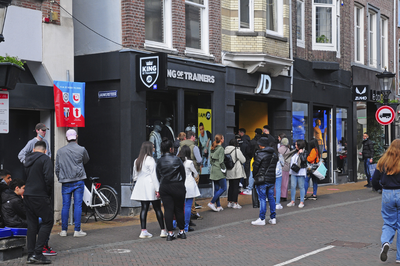 900260 Afbeelding van winkelend publiek dat in de rij staat voor de ingang van sportkledingwinkel JD Sports (Steenweg ...